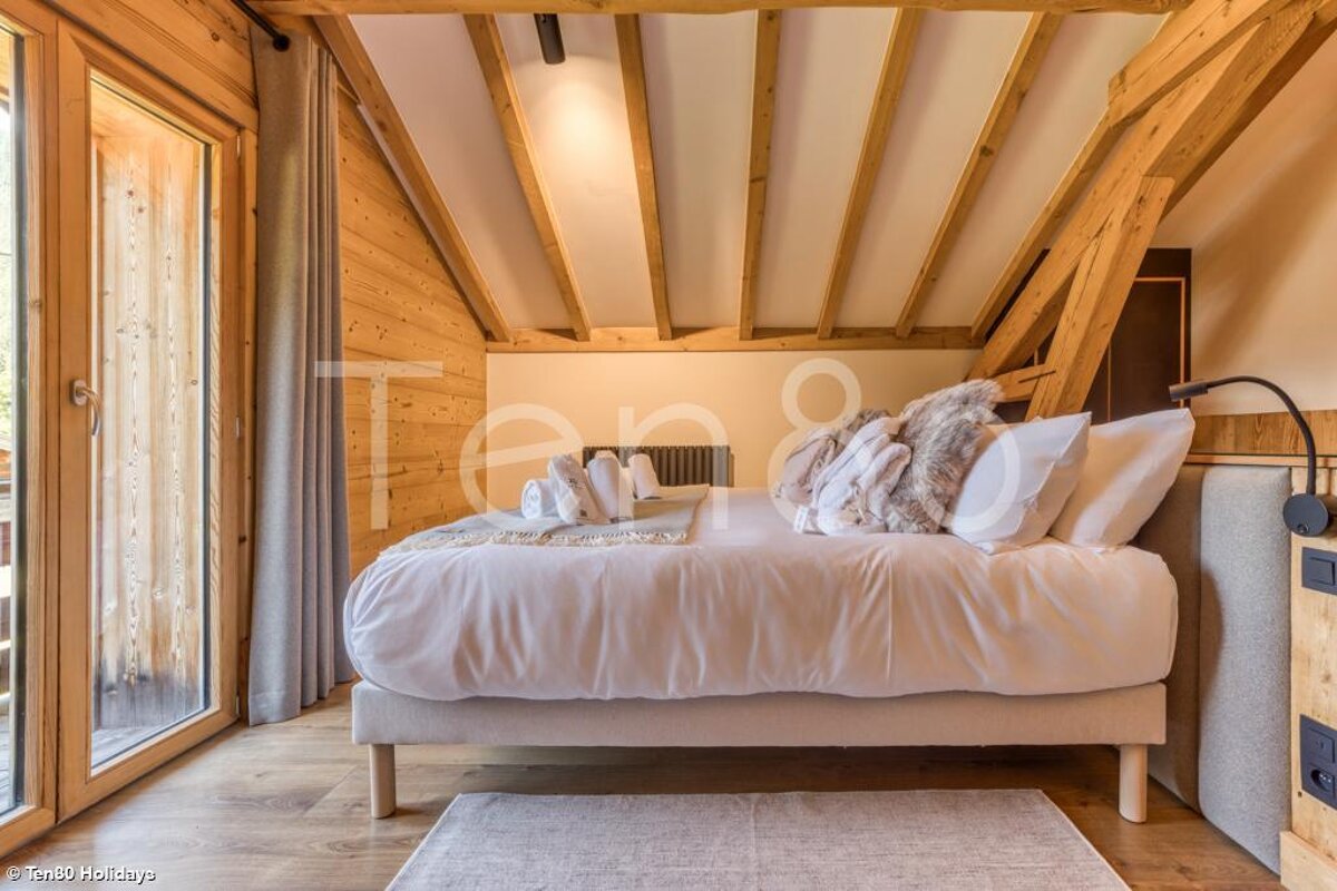 A bed with white sheets and pillows in a room with a sign that says ten8 holidays