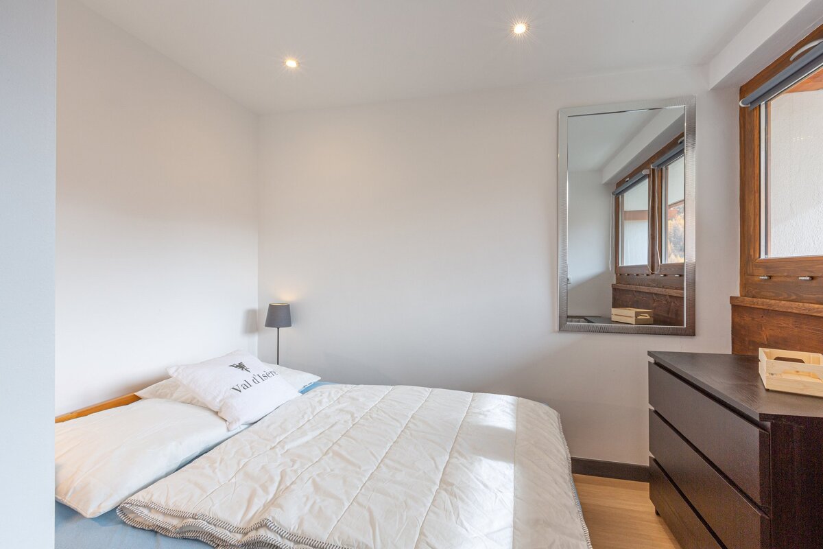 A bright bedroom featuring a white bed with a 