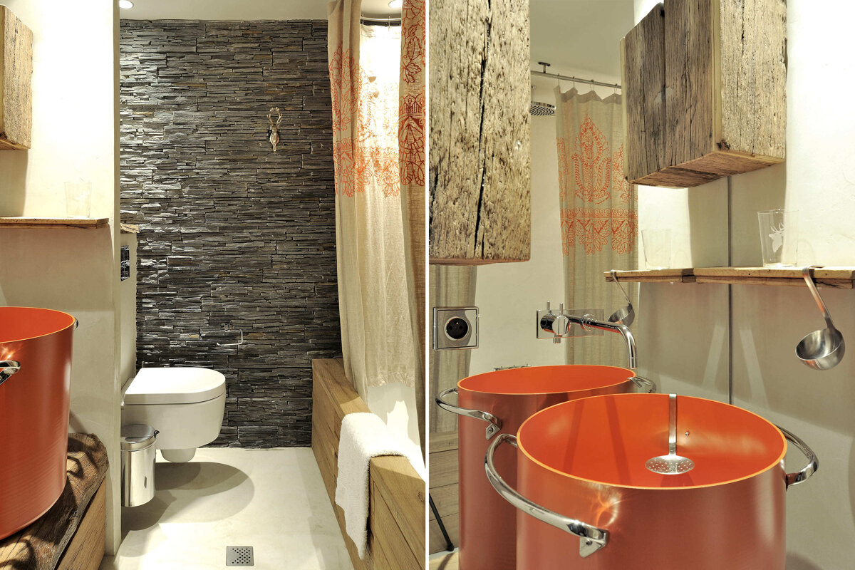 A bathroom with two orange sinks and a stone wall