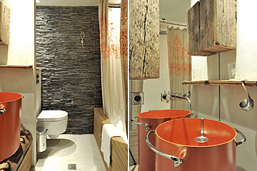 A bathroom with two orange sinks and a stone wall