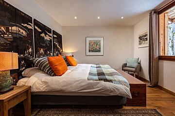 A bedroom with a large bed and paintings on the wall