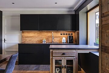 A kitchen with black cabinets and a wooden counter top