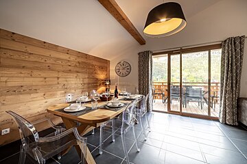 A dining room with a table and chairs and a clock on the wall