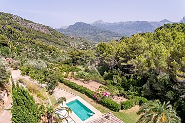 An aerial view of a swimming pool surrounded by trees and mountains