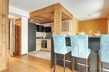 A kitchen with a wooden ceiling and blue chairs