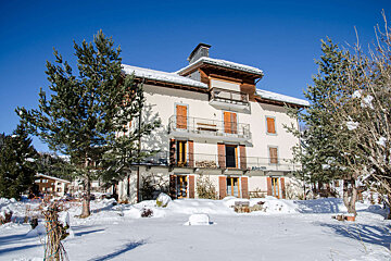 A large white building with balconies and trees in front of it