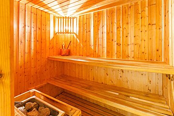 A wooden sauna with a bucket on the shelf