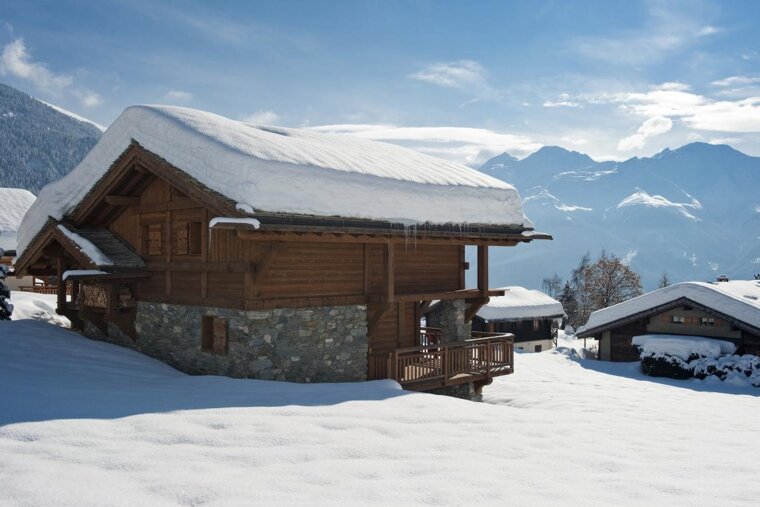 A snow covered house with mountains in the background