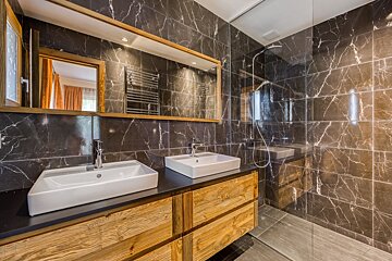 A bathroom with two sinks and a walk in shower