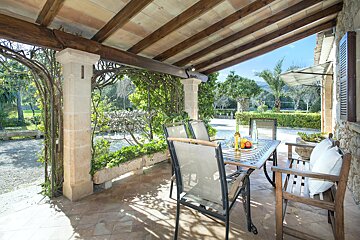 A patio with a table and chairs under a wooden roof