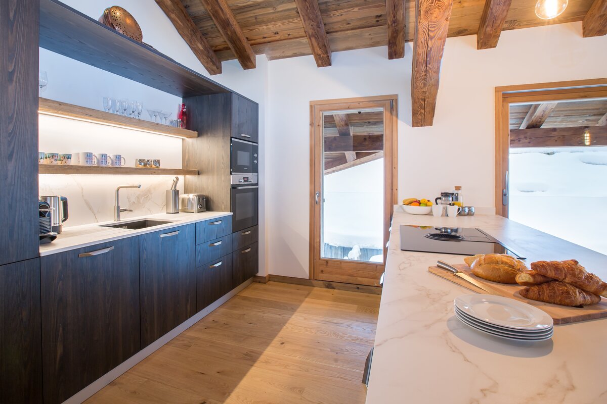 A kitchen with a cutting board with croissants on it
