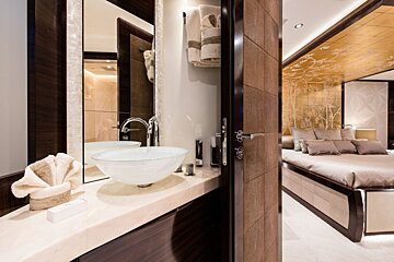A bathroom with a sink and a mirror next to a bed