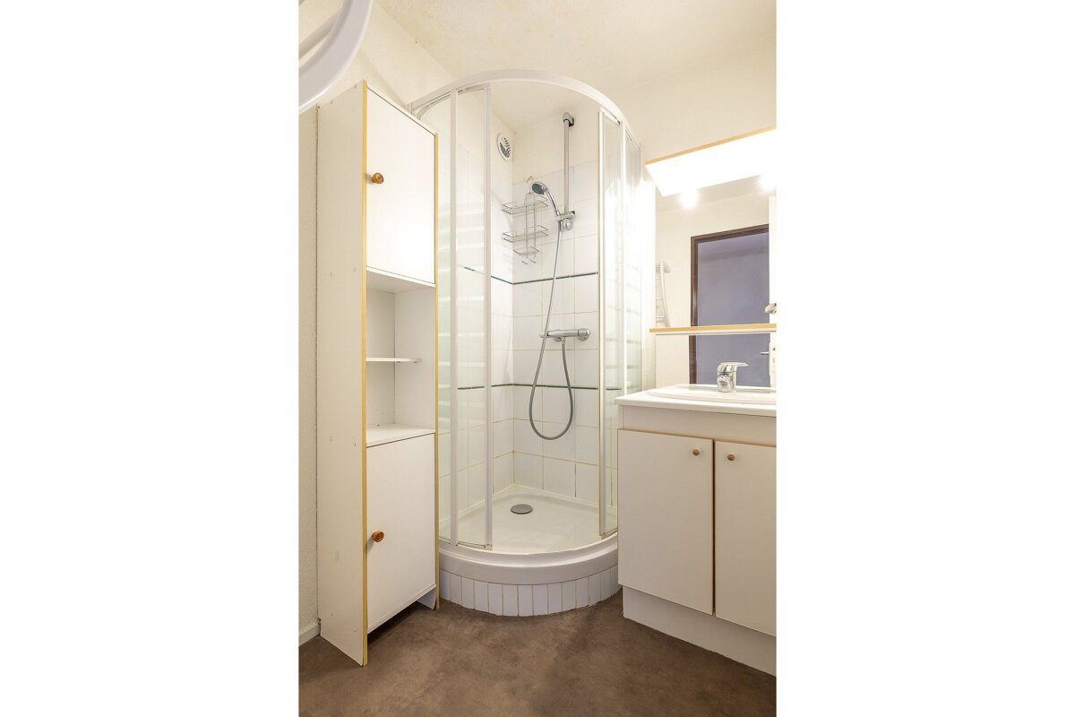 A bathroom with a walk in shower and a sink