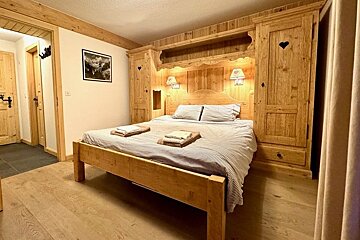 Cozy alpine bedroom featuring a wooden bed framed by rustic built-in wardrobes with heart cutouts.