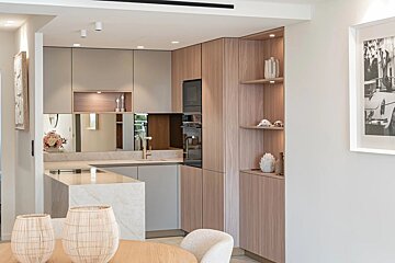 Elegant modern kitchen with light wood and grey cabinets, marble island, built-in appliances, and woven decor in the foreground.