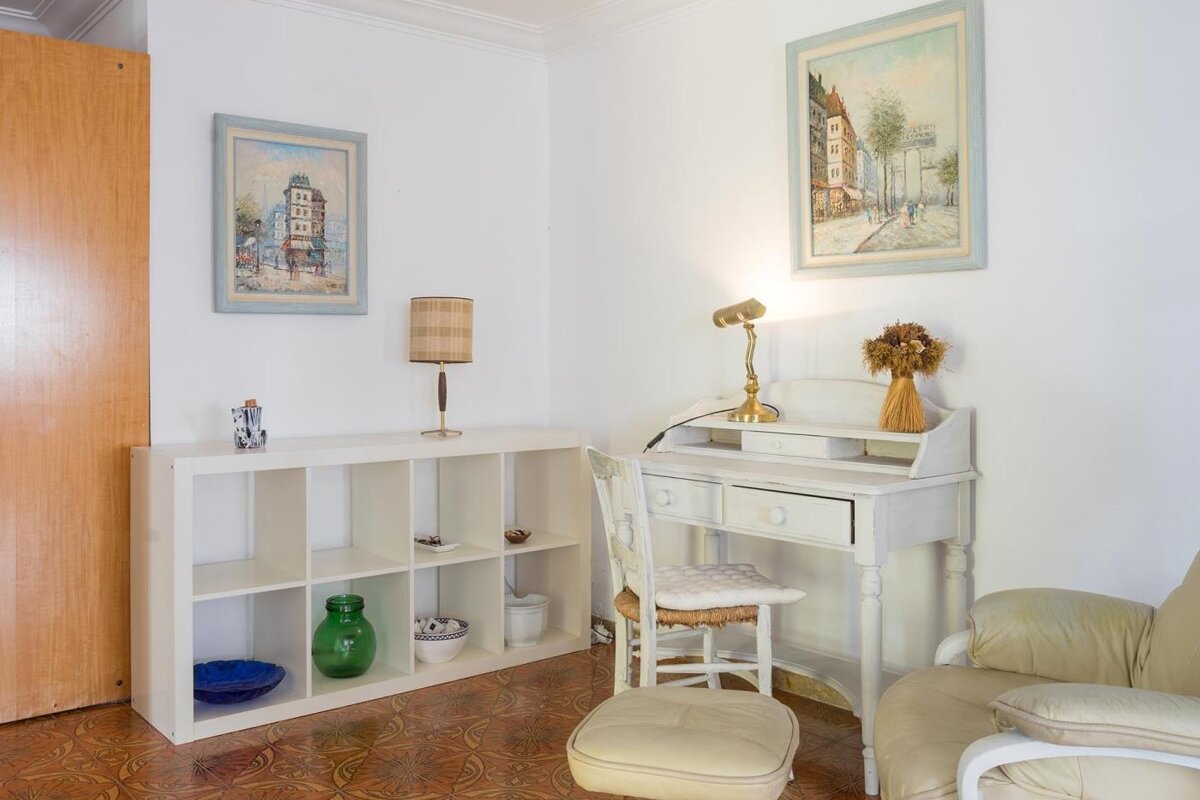 A room with two paintings on the wall and a desk