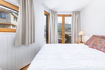 A bedroom with a bed and a window with mountains in the background