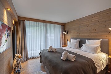 A bedroom with a large bed and a television on the wall