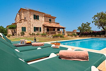 A large stone house with a swimming pool in front of it