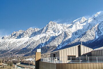 A building with a balcony in front of a snowy mountain