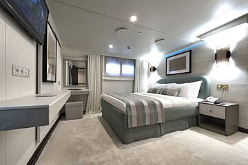 A bedroom with a bed and a television on the wall