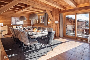 A wooden dining room with a long table and chairs