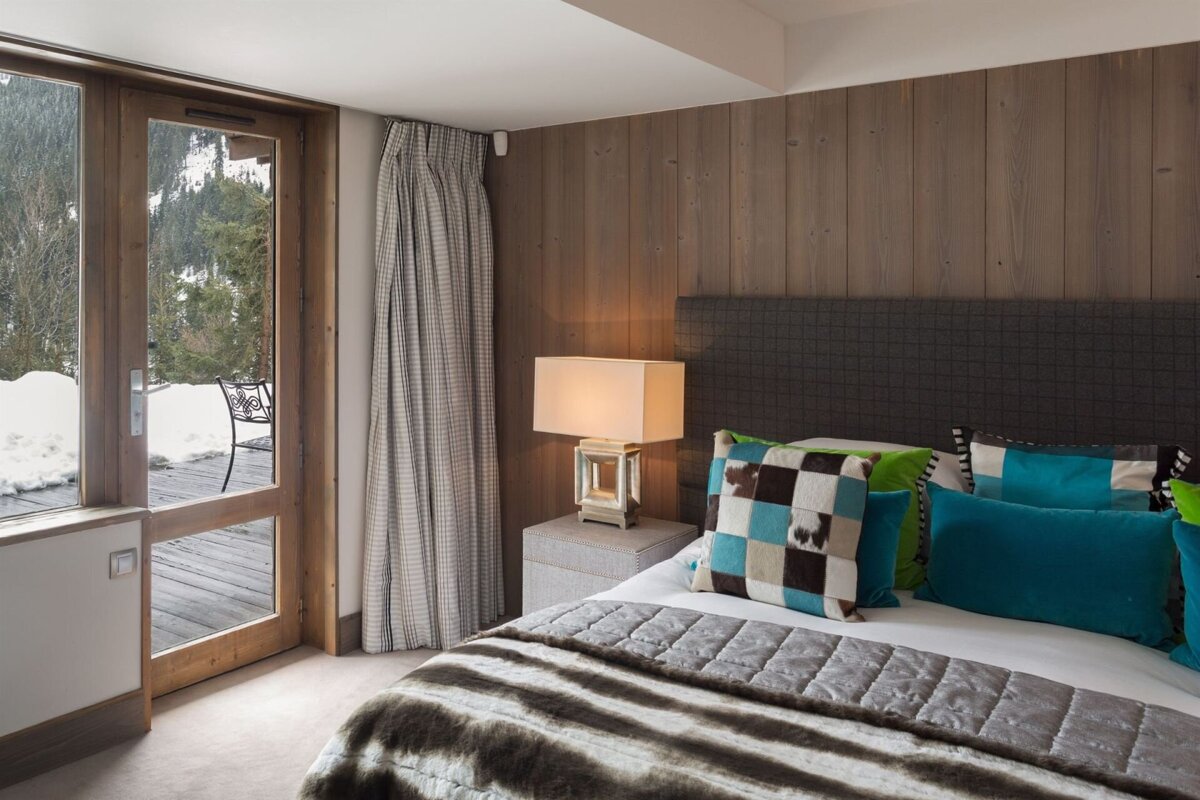 A bedroom with a bed and a table with a lamp on it