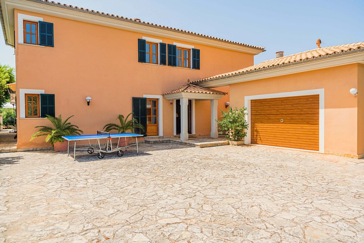 A ping pong table sits in front of a large house
