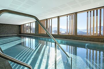 A large indoor swimming pool with mountains in the background