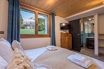 A bedroom with a large bed and a television on the wall
