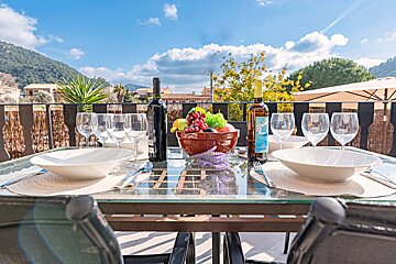A bottle of wine sits on a table with bowls and glasses