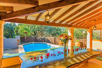 A glass table with flowers on it sits in front of a pool