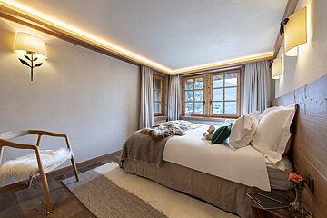 A bedroom with a bed a chair and a window