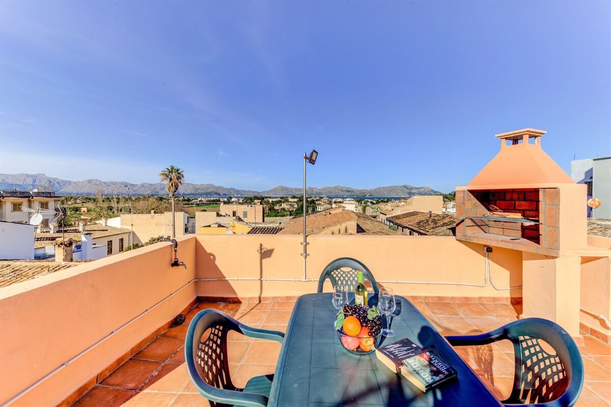 A rooftop patio with a table and chairs and a barbecue