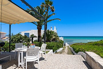 A patio with a table and chairs overlooking the ocean