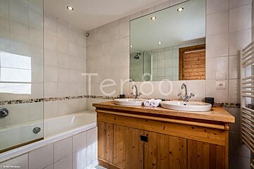 A bathroom with two sinks and a bathtub with the word terroo on the wall