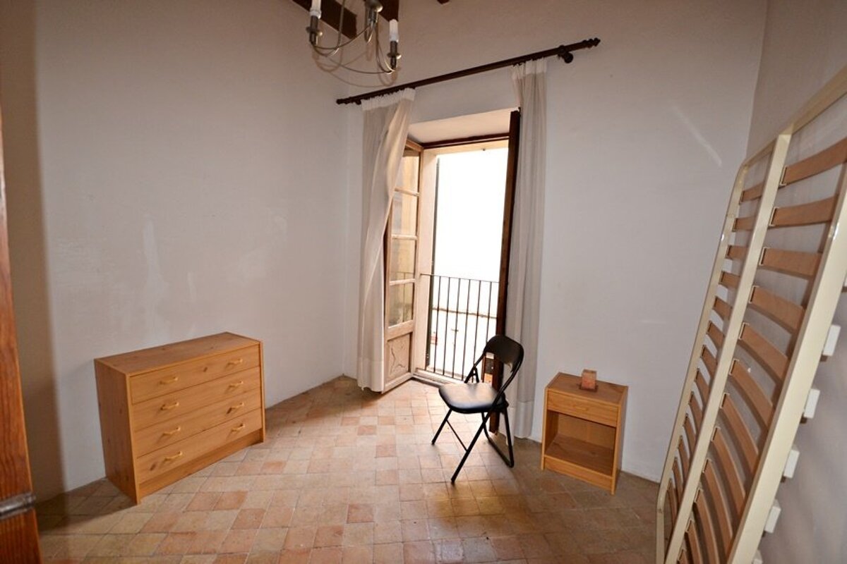 An empty room with a dresser and a chair