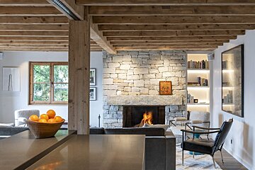 A bowl of oranges sits in front of a fireplace in a living room