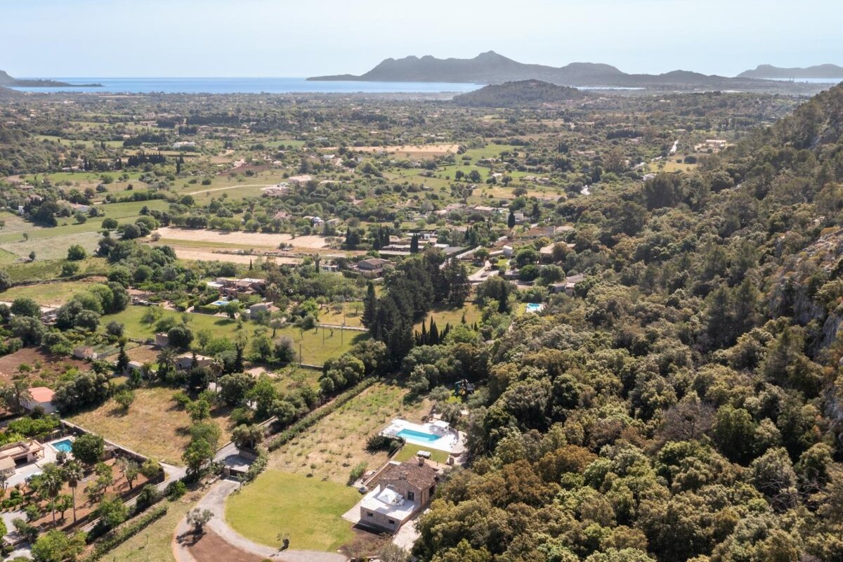 An aerial view of a lush green valley with mountains in the background