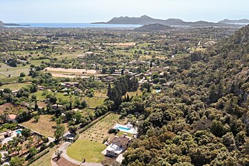 An aerial view of a lush green valley with mountains in the background