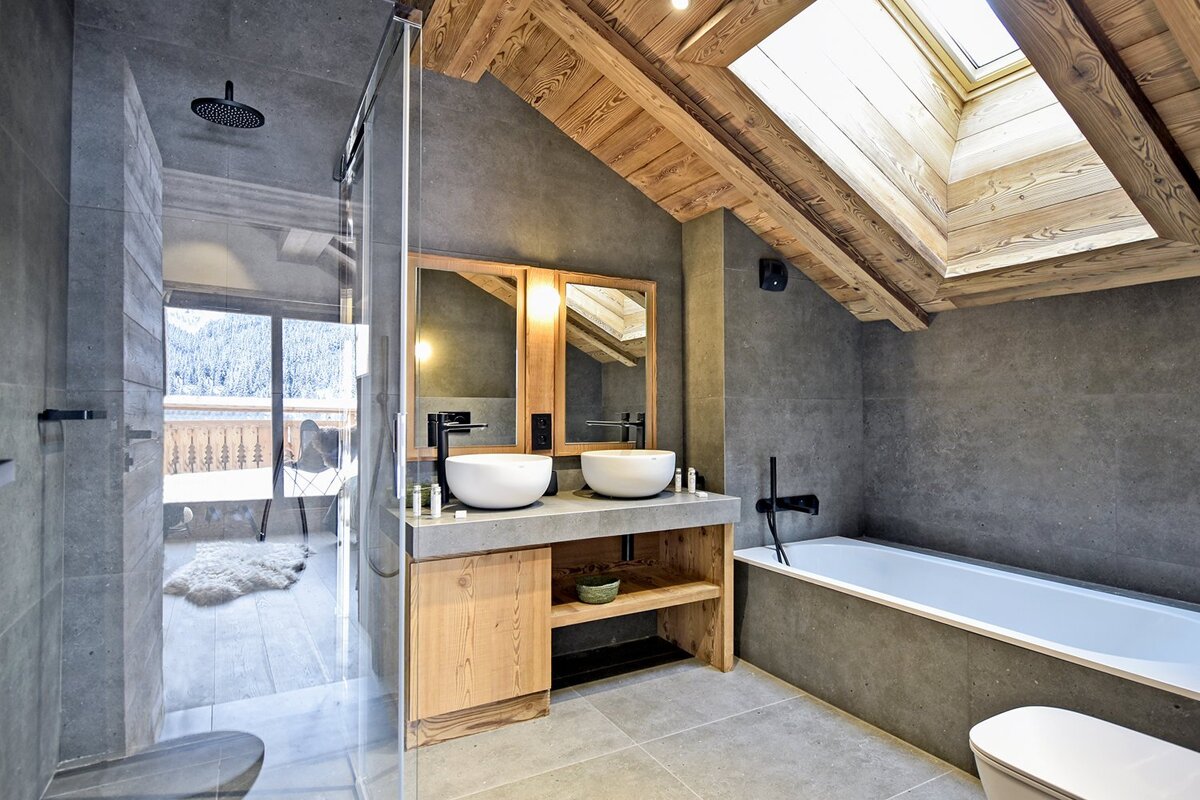 A bathroom with two sinks and a bathtub under a skylight