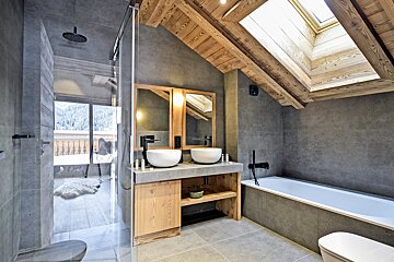 A bathroom with two sinks and a bathtub under a skylight