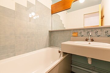 A bathroom with a bathtub and a sink with flowers on the wall