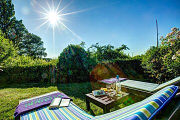 A bottle of wine sits on a table between two lounge chairs