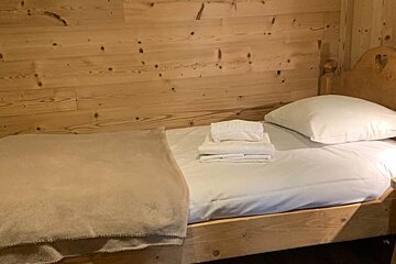 A wooden bed with white sheets and pillows