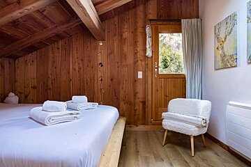 A bedroom with two beds and a chair and a painting of a deer on the wall