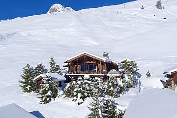 A snowy mountain with a house in the foreground