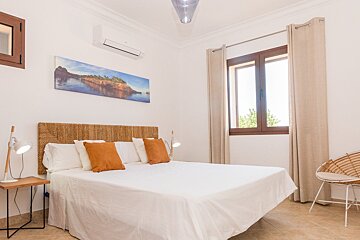 A bedroom with a painting on the wall above the bed