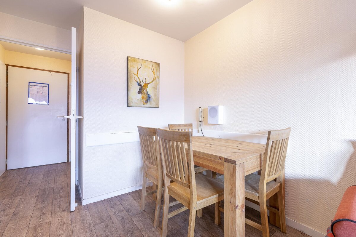 A painting of a deer hangs above a wooden table and chairs