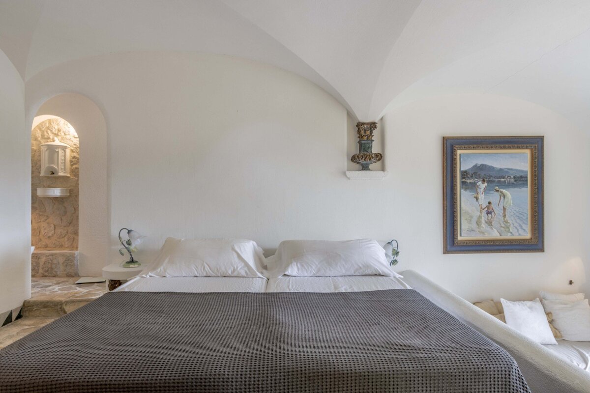A bedroom with a painting on the wall above the bed